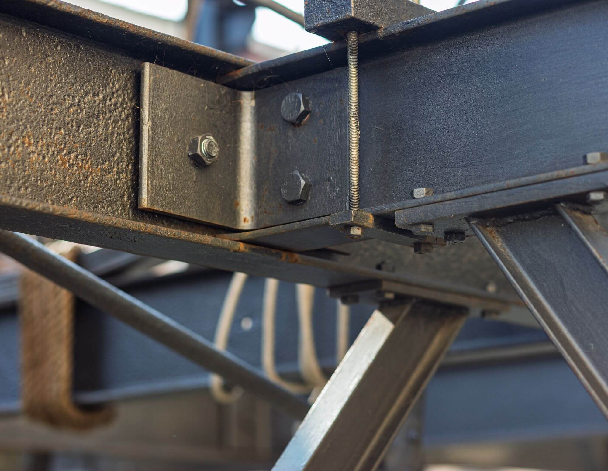 Steel structural connector with bolts and beams, illustrating engineering precision and construction stability.