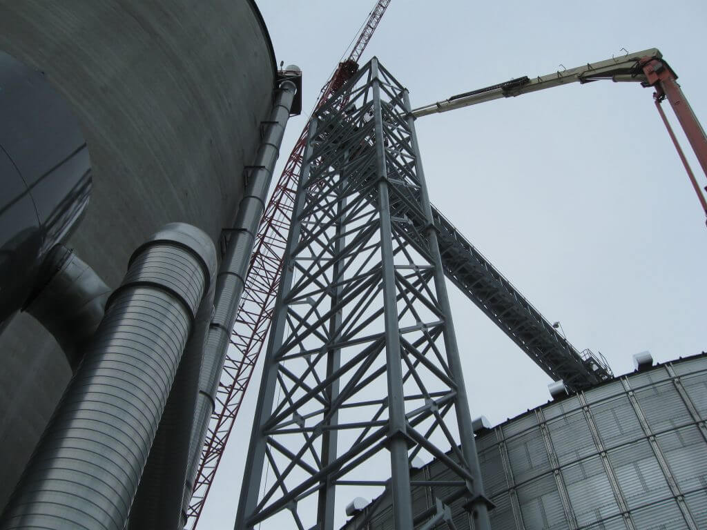 Grain bin construction site with a large metal framework and cranes, showcasing industrial engineering work by Larson Engineering.