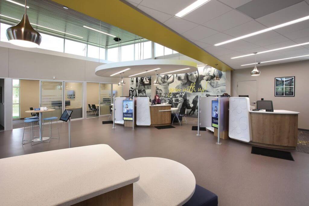 Interior of Prospera Credit Union featuring a modern lobby with teller stations, consultation rooms, and a high ceiling over 20 feet tall, enclosed in glass.