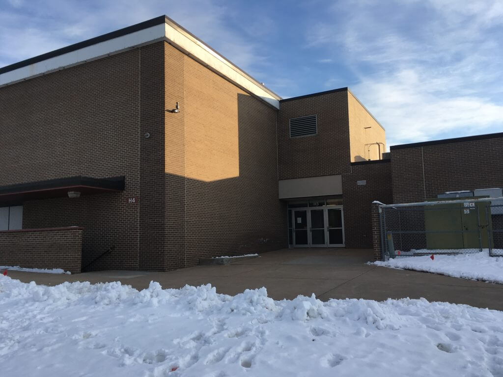 Exterior view of a brick building at Manawa School District, featuring a secure entrance and surrounded by snow-covered ground.